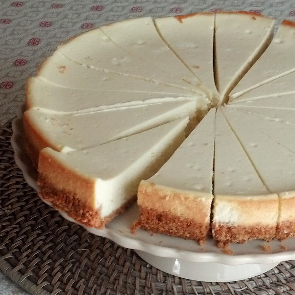 A plain cheesecake cut into slices on a white cake stand