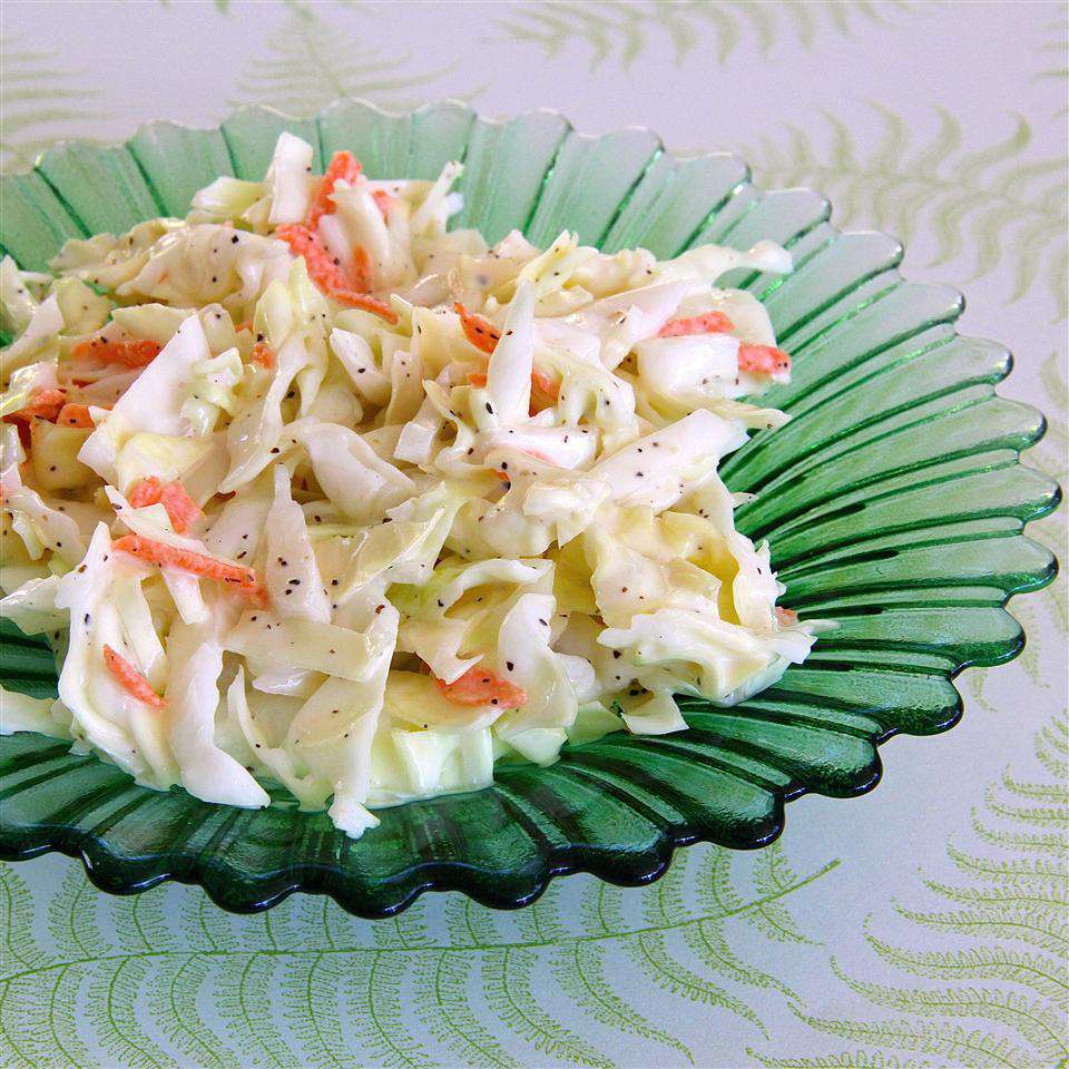 a serving of creamy-looking coleslaw with green cabbage and shredded carrots served on a green fluted glass plate