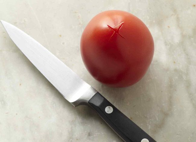 tomato with x cut into the base with knife