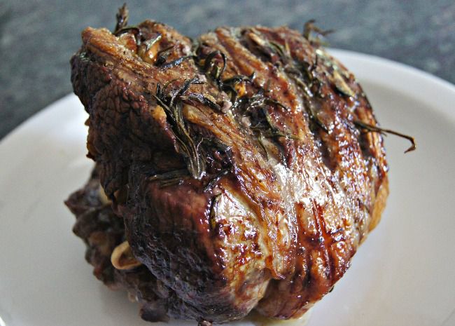 a lamb roast baked with rosemary on a white platter