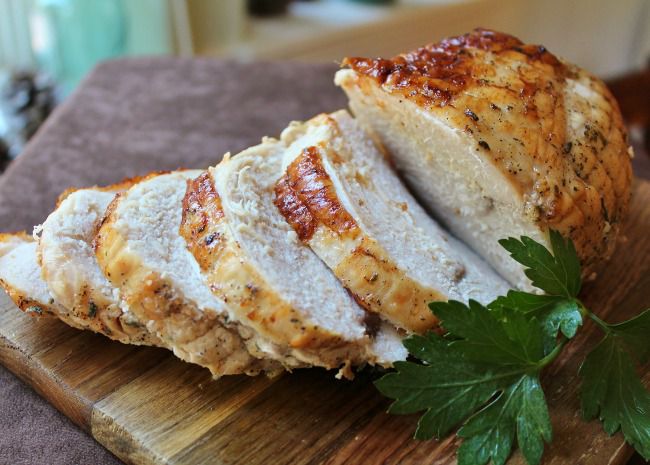 turkey breast on a cutting board, cut into slices, with a parsley garnish