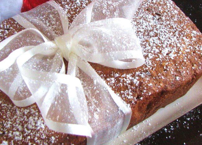 closeup of a loaf cake dusted with powdered sugar and tied with a white ribbon