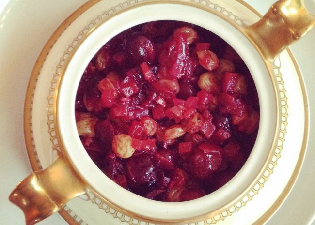 a top-down view of a colorful cranberry chutney in fine gold-rimmed china