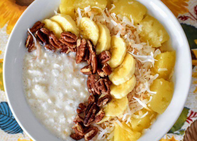 top-down view of a shallow bowl of cottage cheese topped with rows of pecan halves, banana slices, toasted coconut, and pineapple chunks