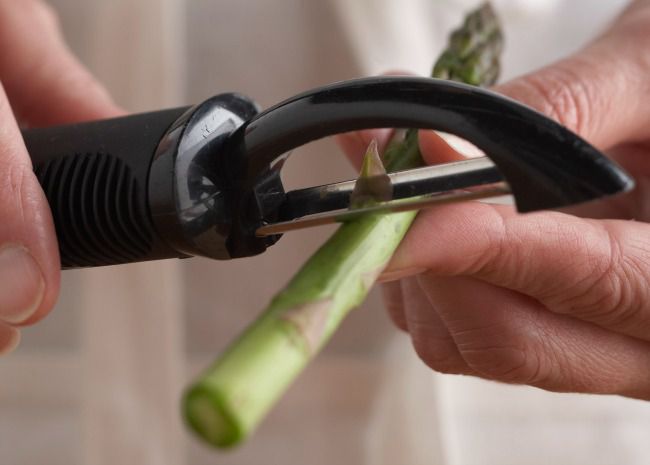 peeling fresh asparagus stems with a vegetable peeler