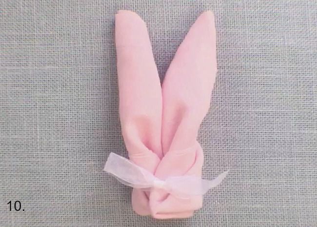 Pink linen napkins folded into bunny ears tied with ribbon.