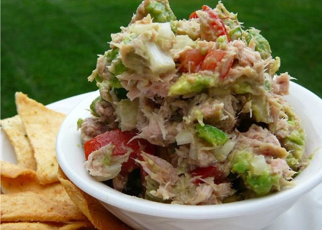 A white bowl filled with tuna salad served with crackers