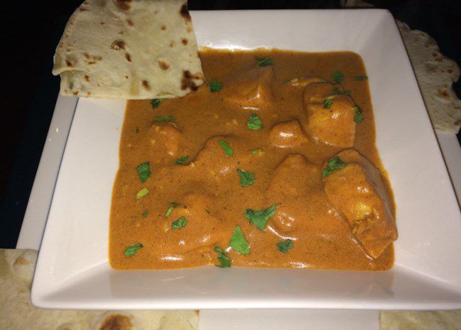 chicken tikka masala in a bowl with naan on the side