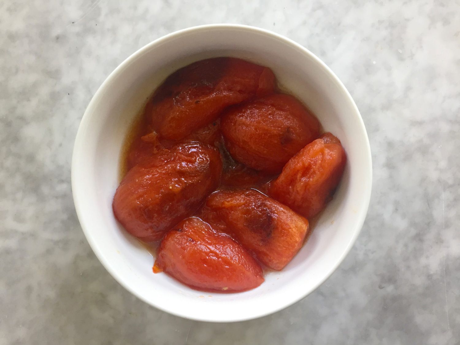 Fire-roasted tomatoes without skins in bowls.