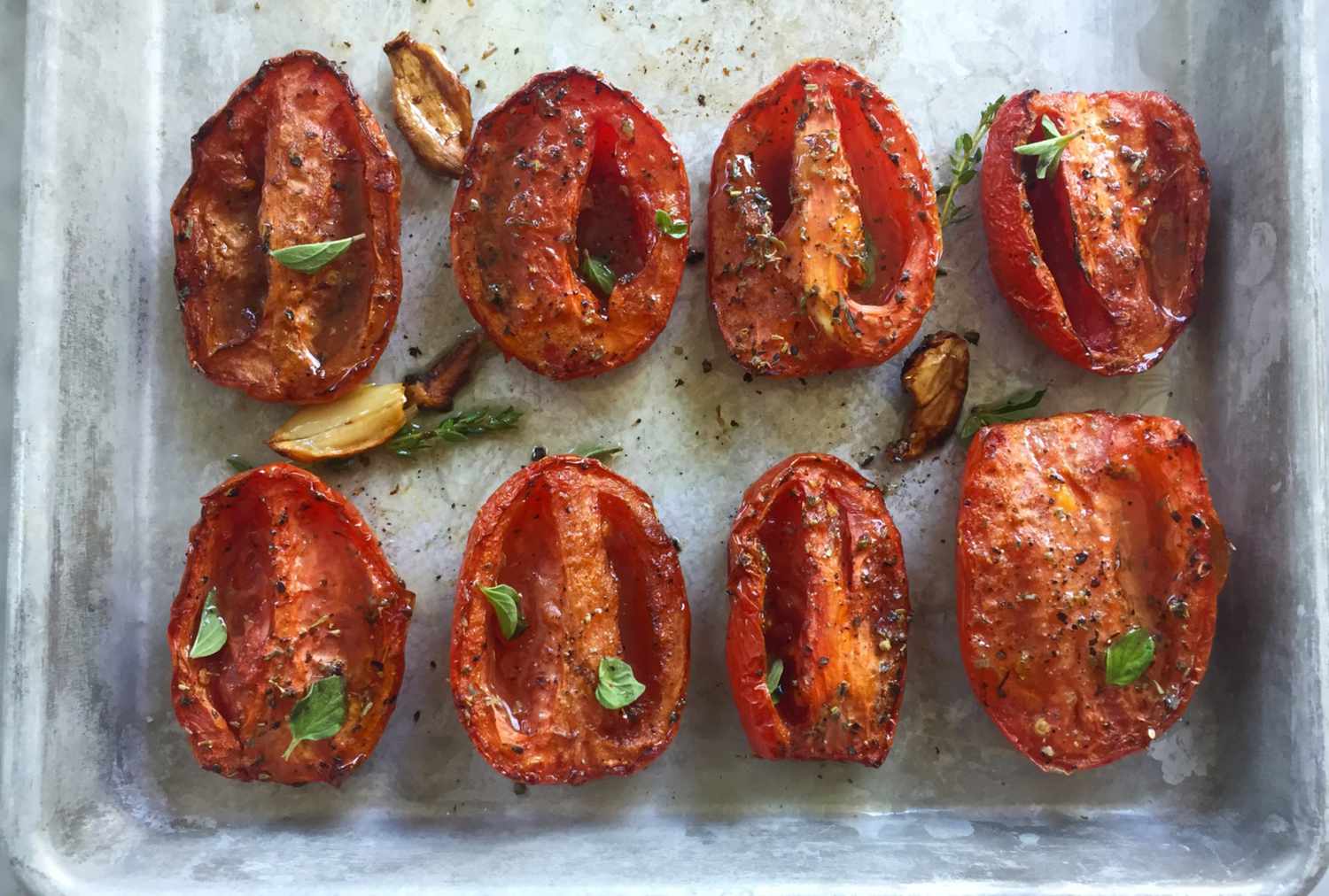 Roasted roma tomatoes on a sheet tray.