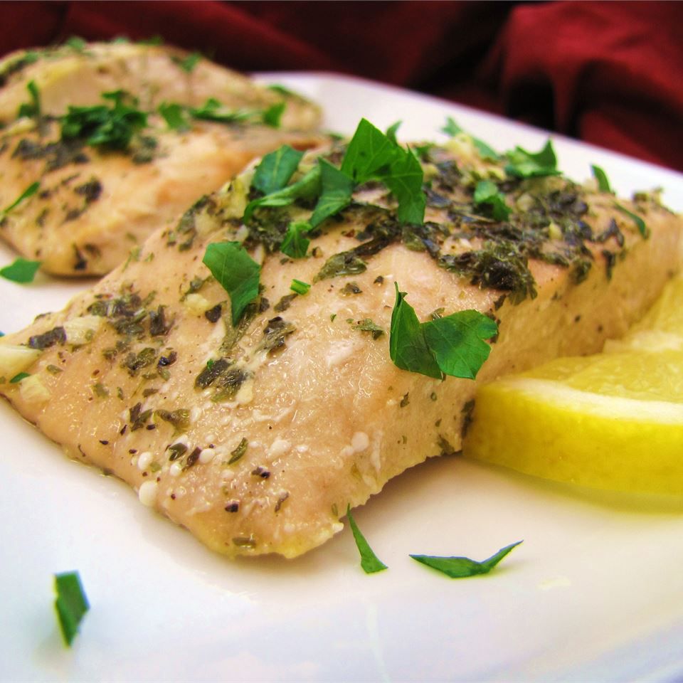 two salmon fillets garnished with fresh chopped parsley and a lemon slice