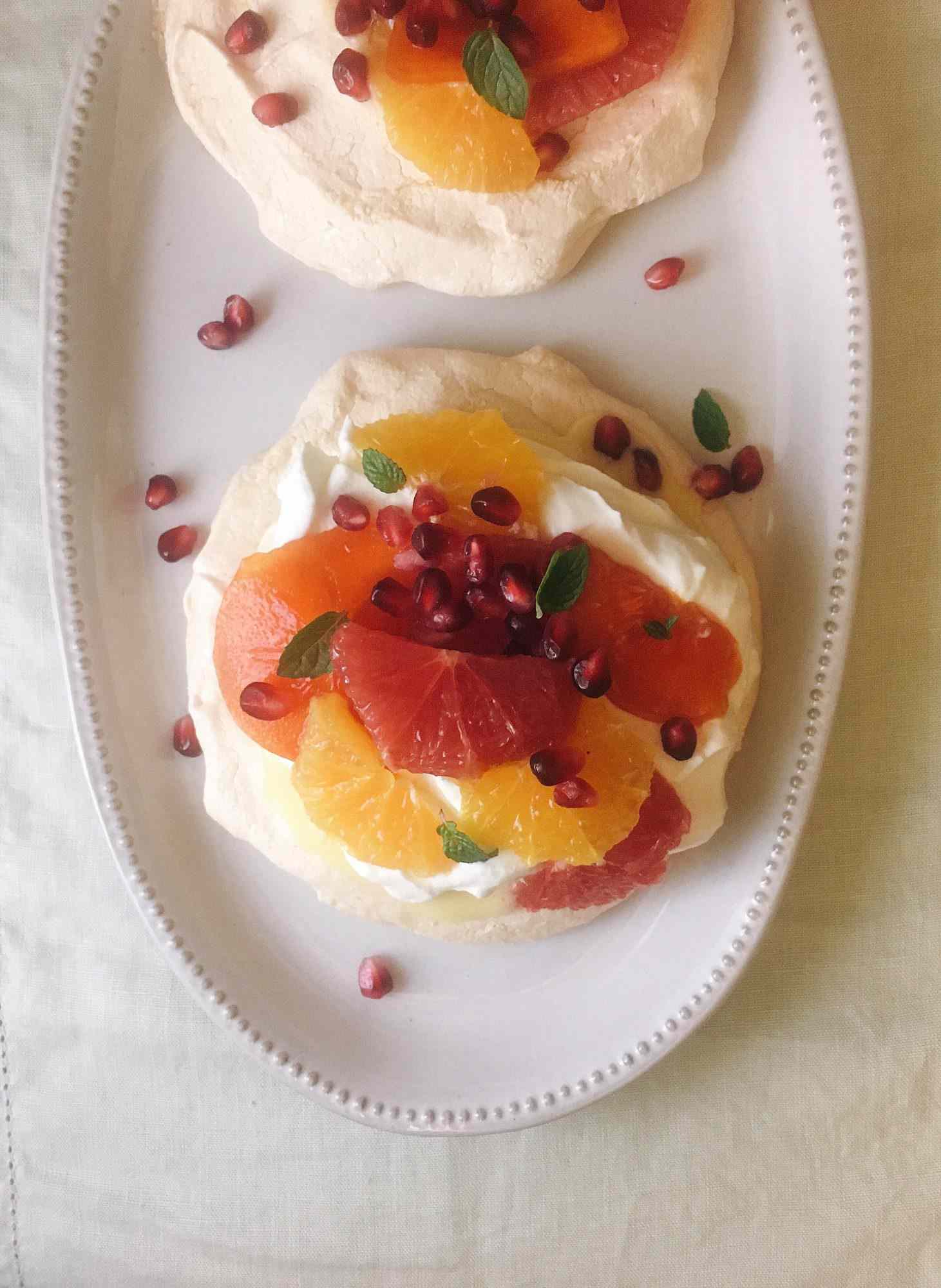 pavlova meringue topped with citrus fruit and pomegranate seeds