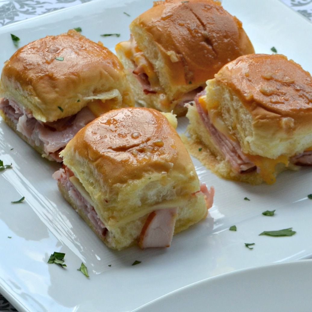 four slider-sized ham sandwiches on a square white plate