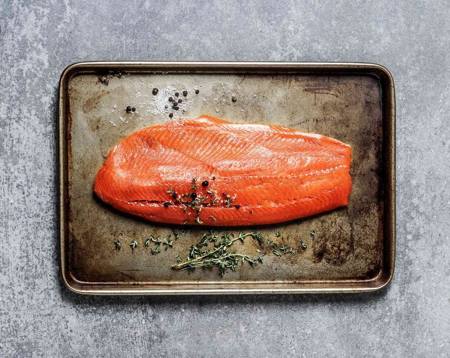Raw salmon fillet on metal tray