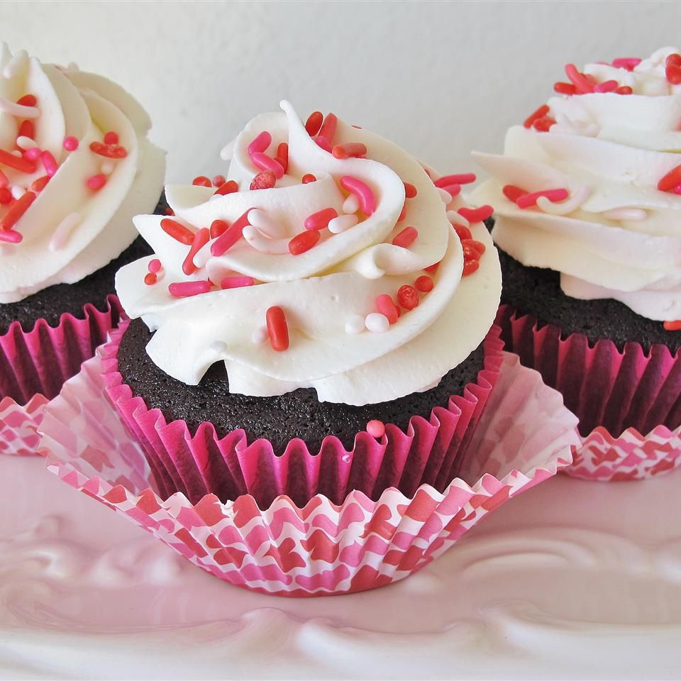 three Valentine's Day cupcakes decorated with white frosting and red, white, and pink sprinkles