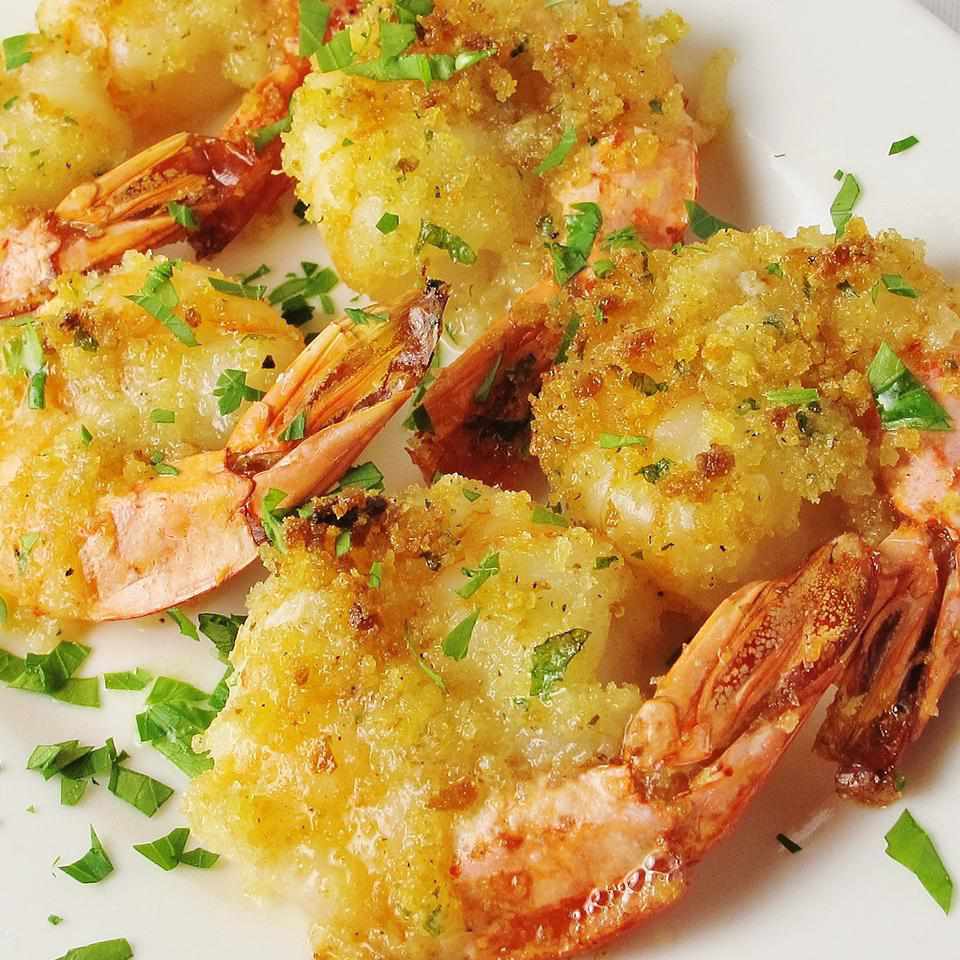 closeup of four golden-brown baked shrimp garnished with chopped parsley