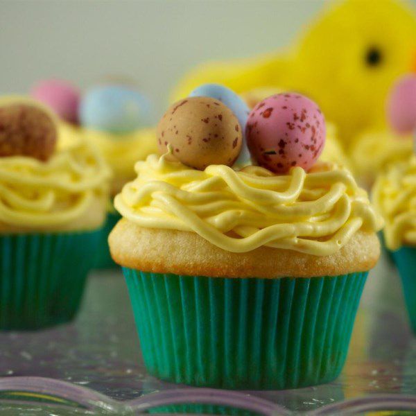 Easter cupcakes decorated to look like birds' nests, with yellow frosting and candy eggs