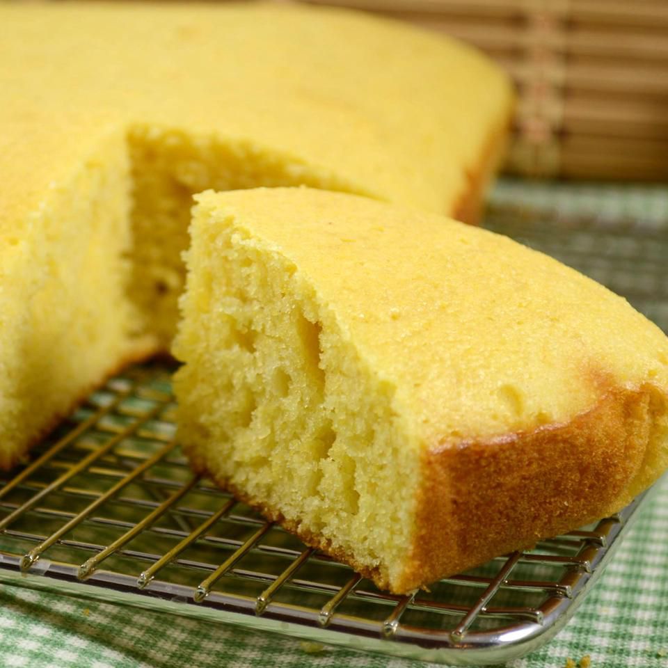 Cornbread on a cooling rack with a cut wedge in the foreground