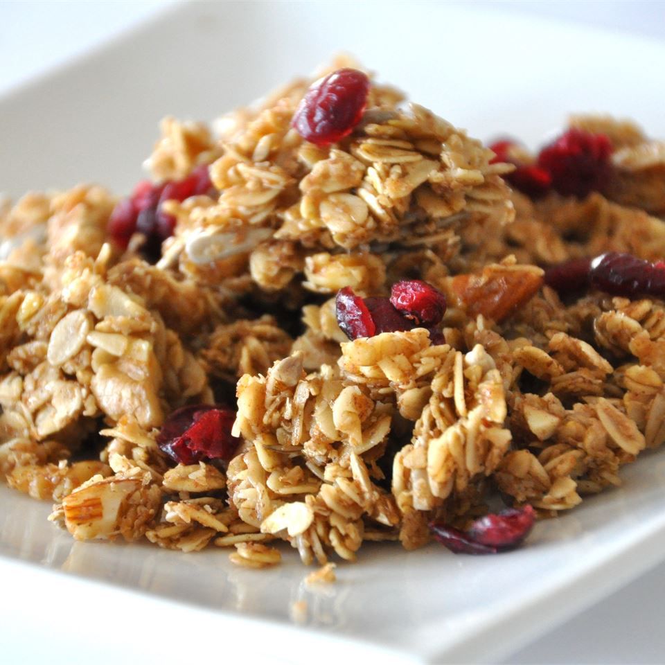 A shallow white dish with a scoop of homemade granola with dried cranberries