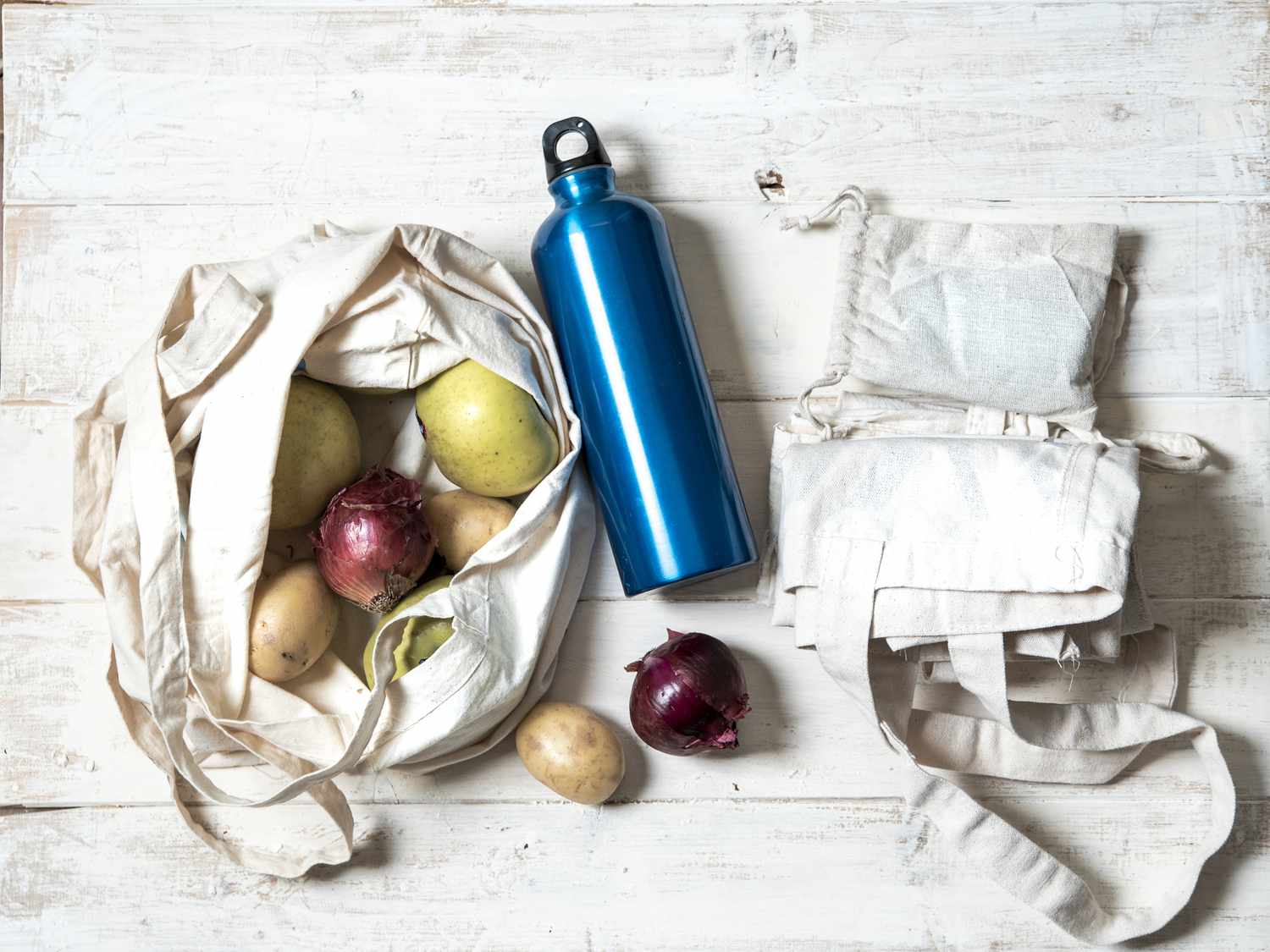 cotton shopping bags with vegetables inside and an aluminum water bottle