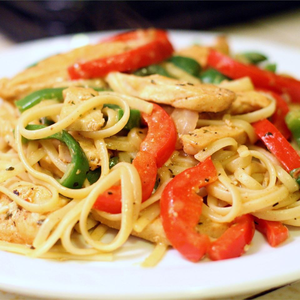 a colorful plate of chicken breast strips and red and green bell peppers tossed with spaghetti