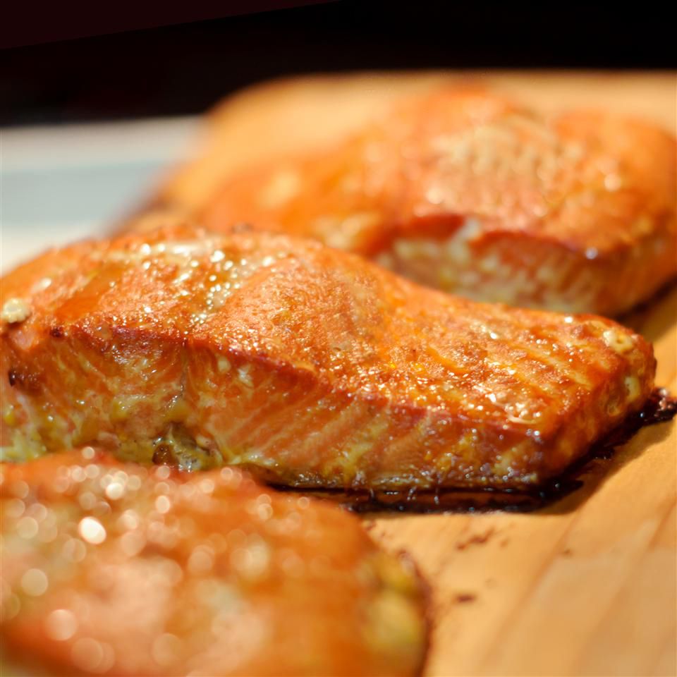 three center-cut salmon fillets on a wood plank for grilling