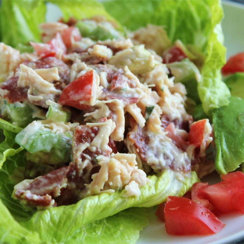 a scoop of colorful-looking chicken salad on a lettuce leaf garnished with tomato wedges