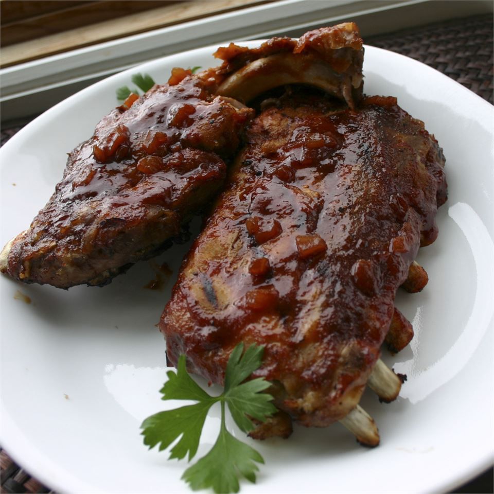 top-down view of two racks of ribs on a white plate, garnished with a sprig of parsley