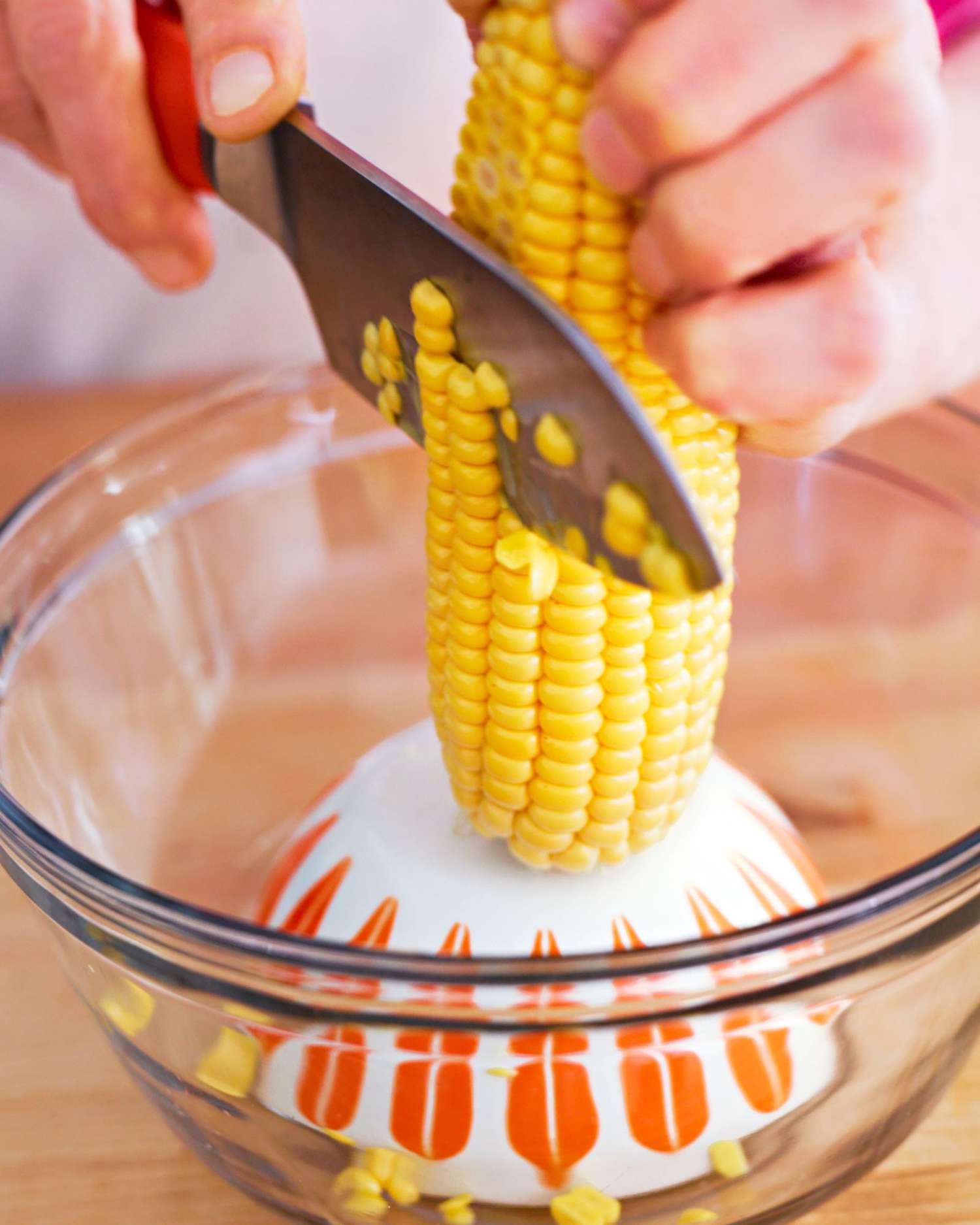 Corn being cut off cob in bowl