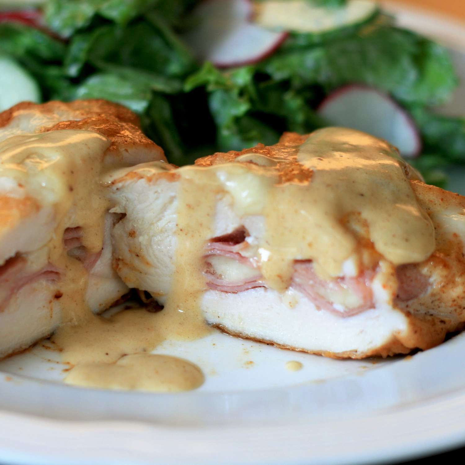 chicken stuffed with ham and cheese with sauce on top