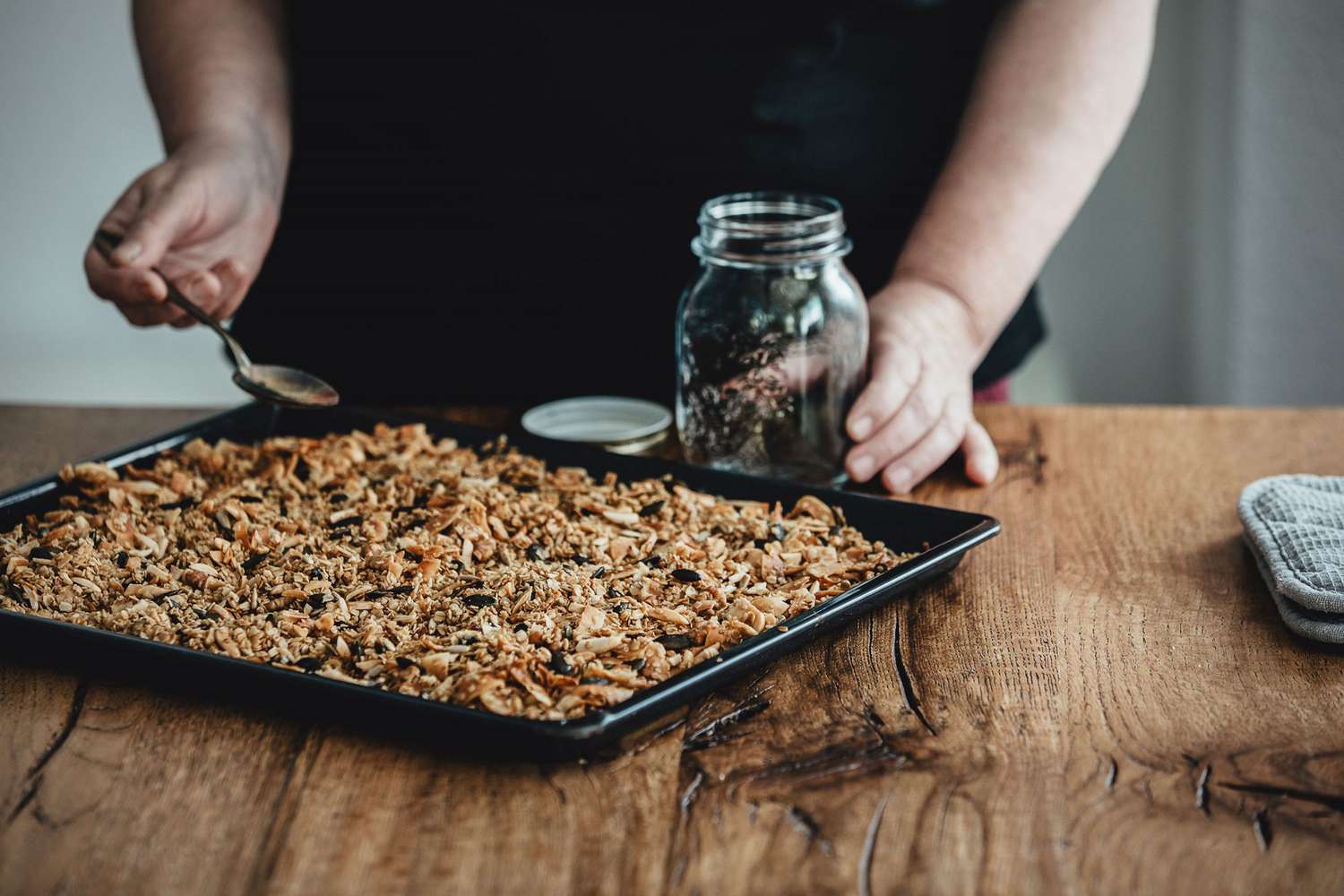 Homemade granola being scooped into a jar