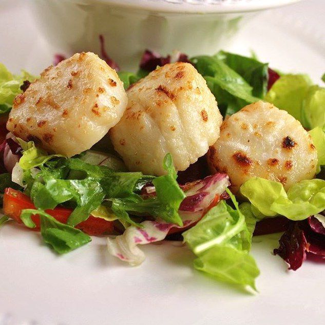 three sea scallops on a bed of salad greens