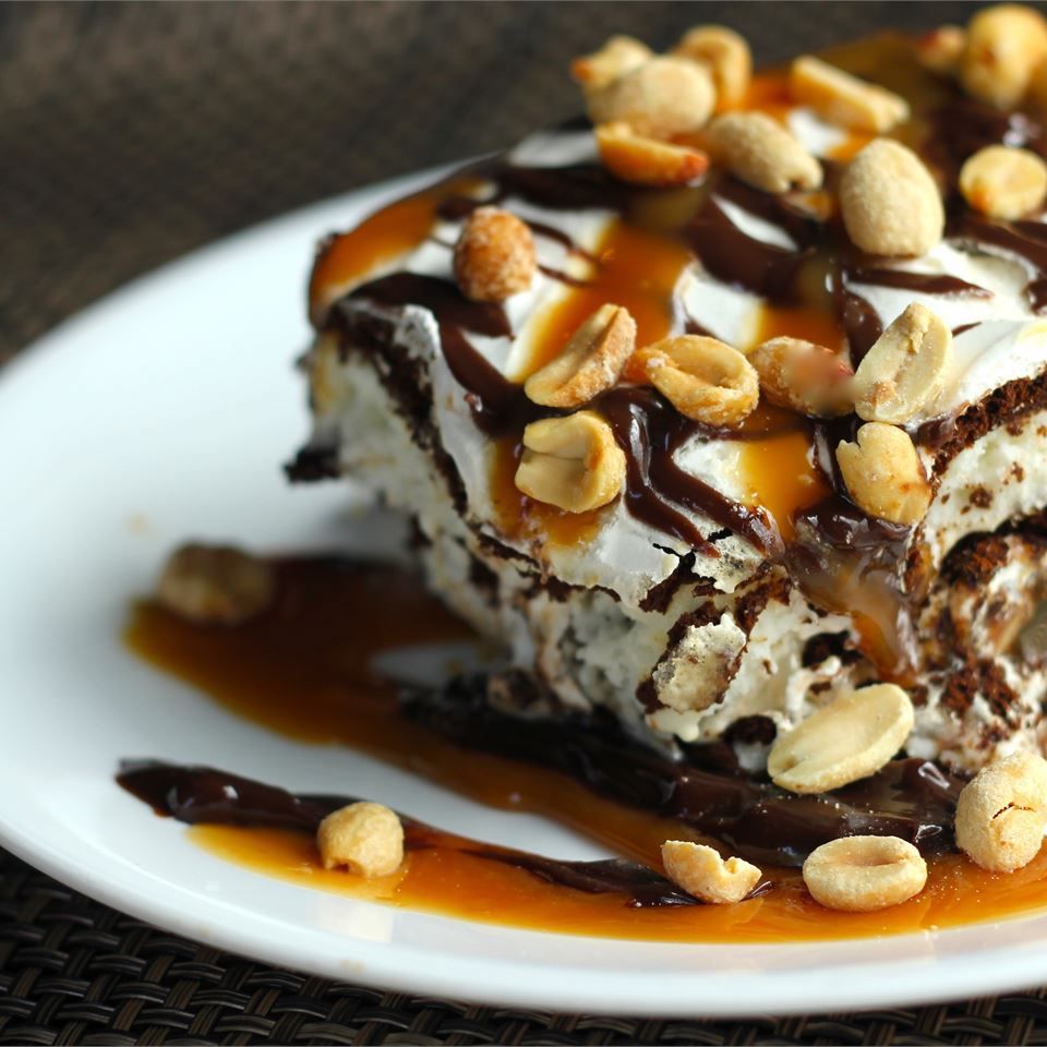 layers of chocolate, caramel, and ice cream are stacked with peanuts on top on a white platter