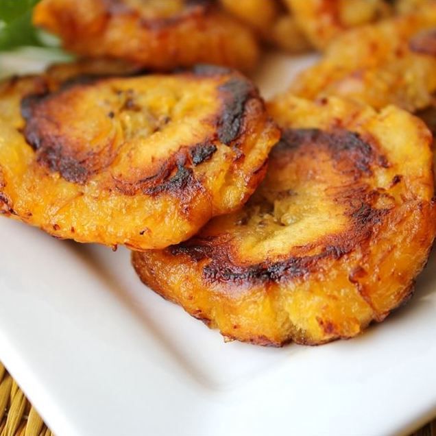 closeup of fried plantain slices on a square white plate