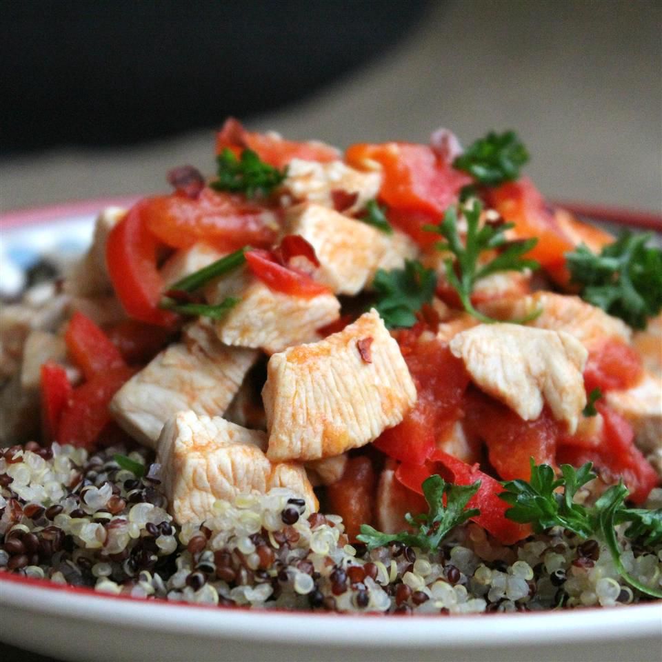 chicken with red peppers and tomatoes served over quinoa