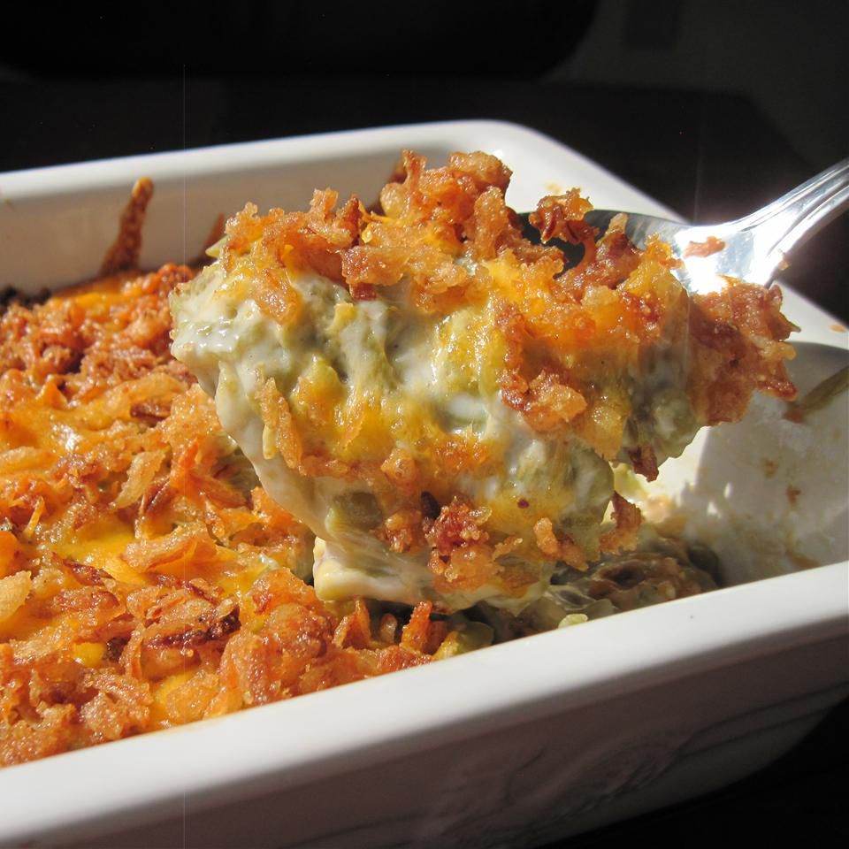 a spatula lifting a serving of golden brown crumb-topped casserole from a white ceramic baking dish