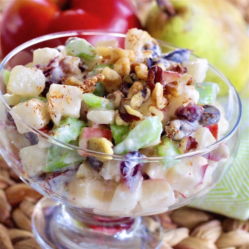 A Waldorf salad with dried cranberries and walnuts in a glass bowl