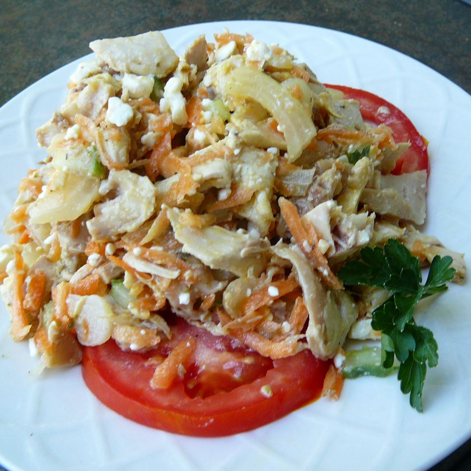 Greek Chicken Salad over sliced tomatoes on a white plate