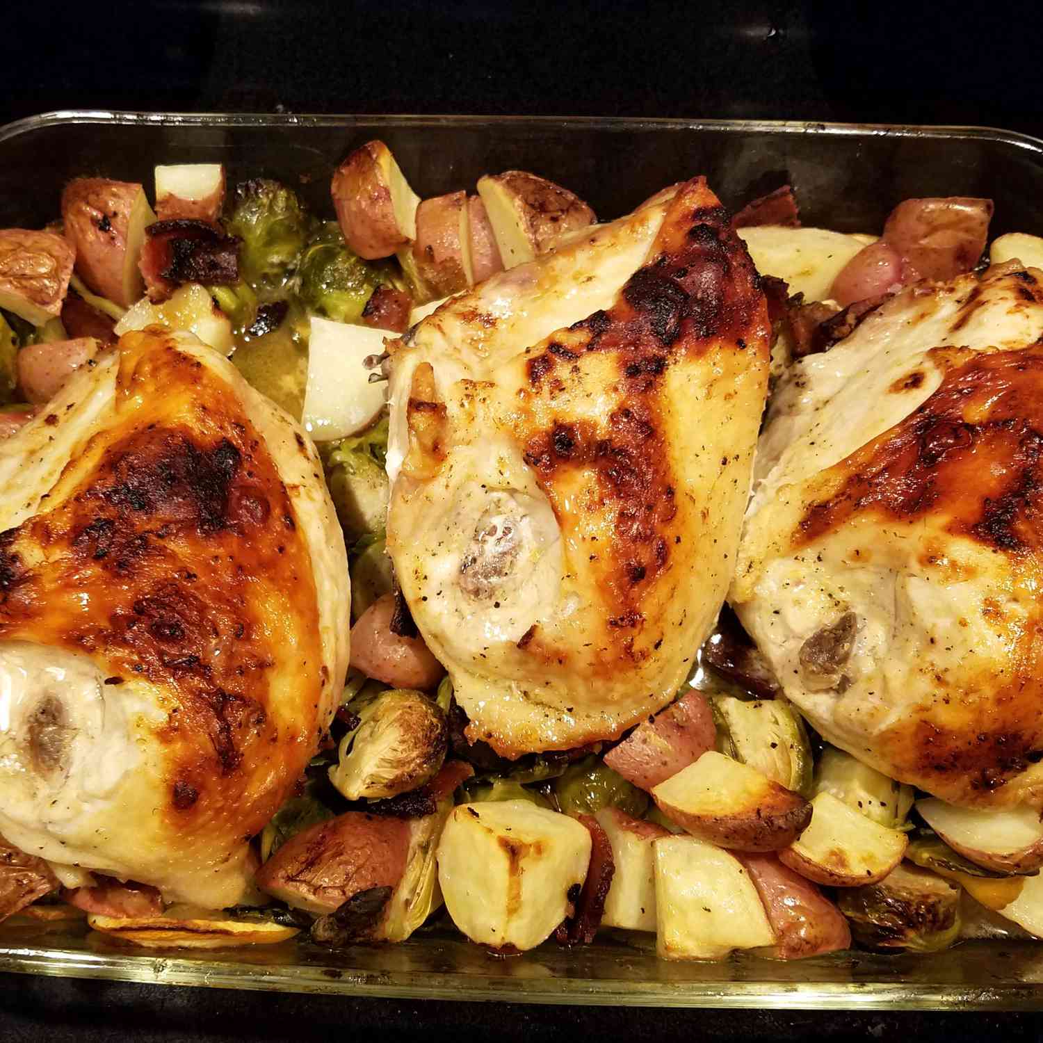Pan-Roasted Chicken with Lemon-Garlic Brussels Sprouts and Potatoes in a glass pan