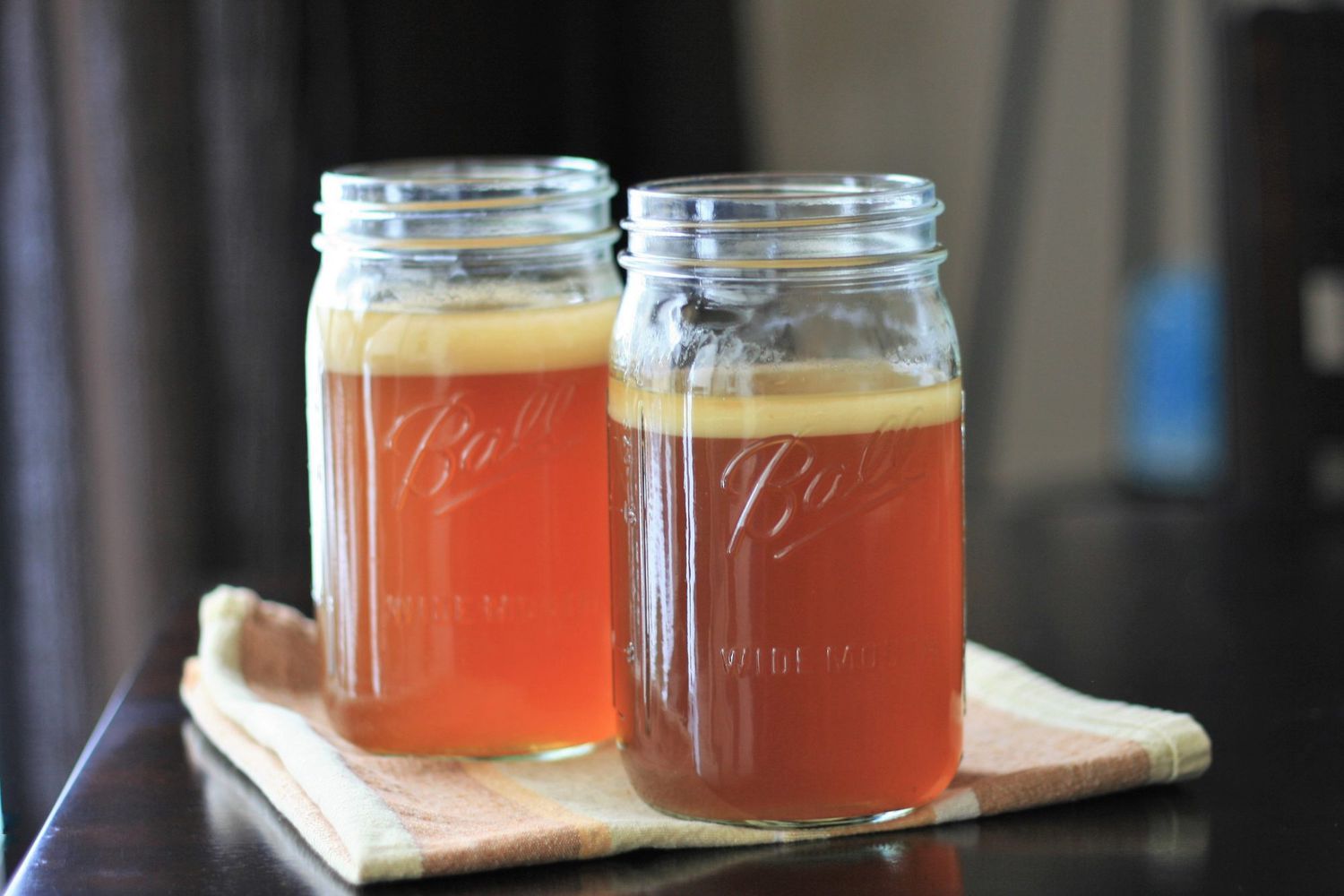 Two mason jars of clear amber-colored stock