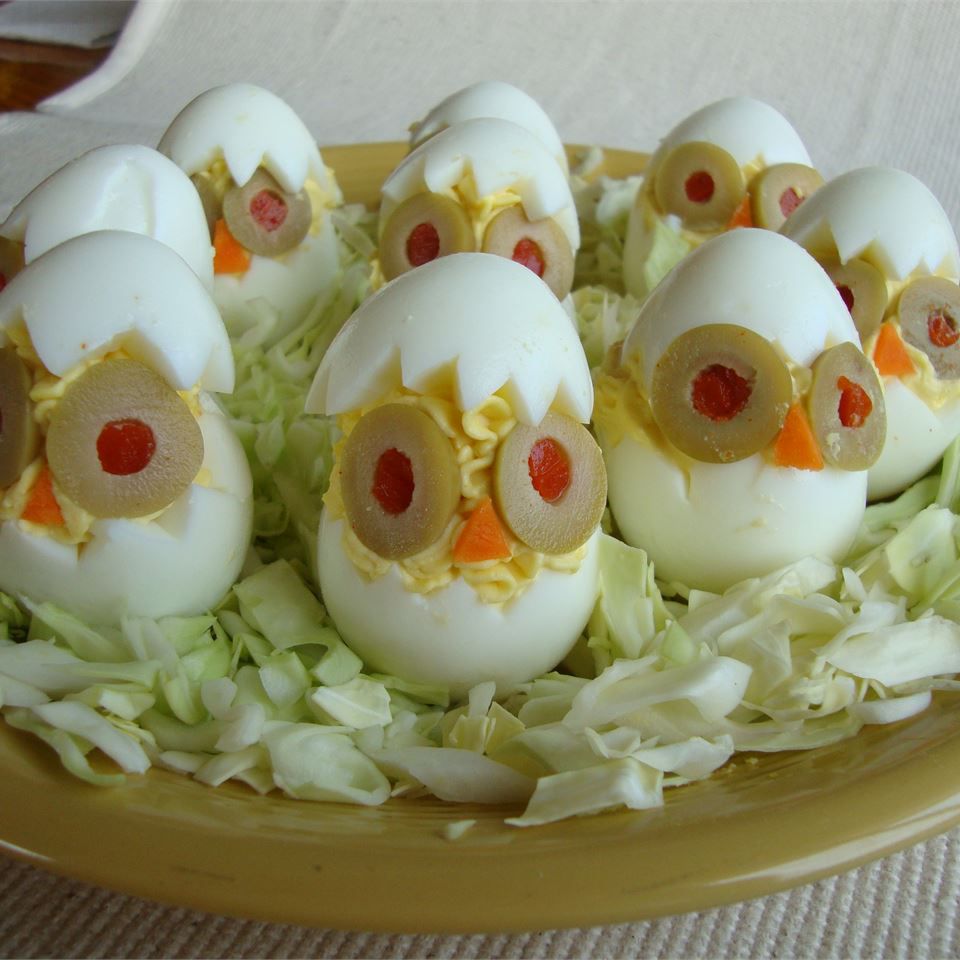 Deviled eggs made by cutting a jagged "shell" edge, with olive eyes and carrot beaks