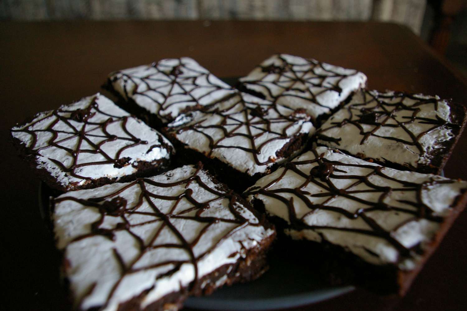 Halloween brownies decorated with white frosting and chocolate spiderwebs