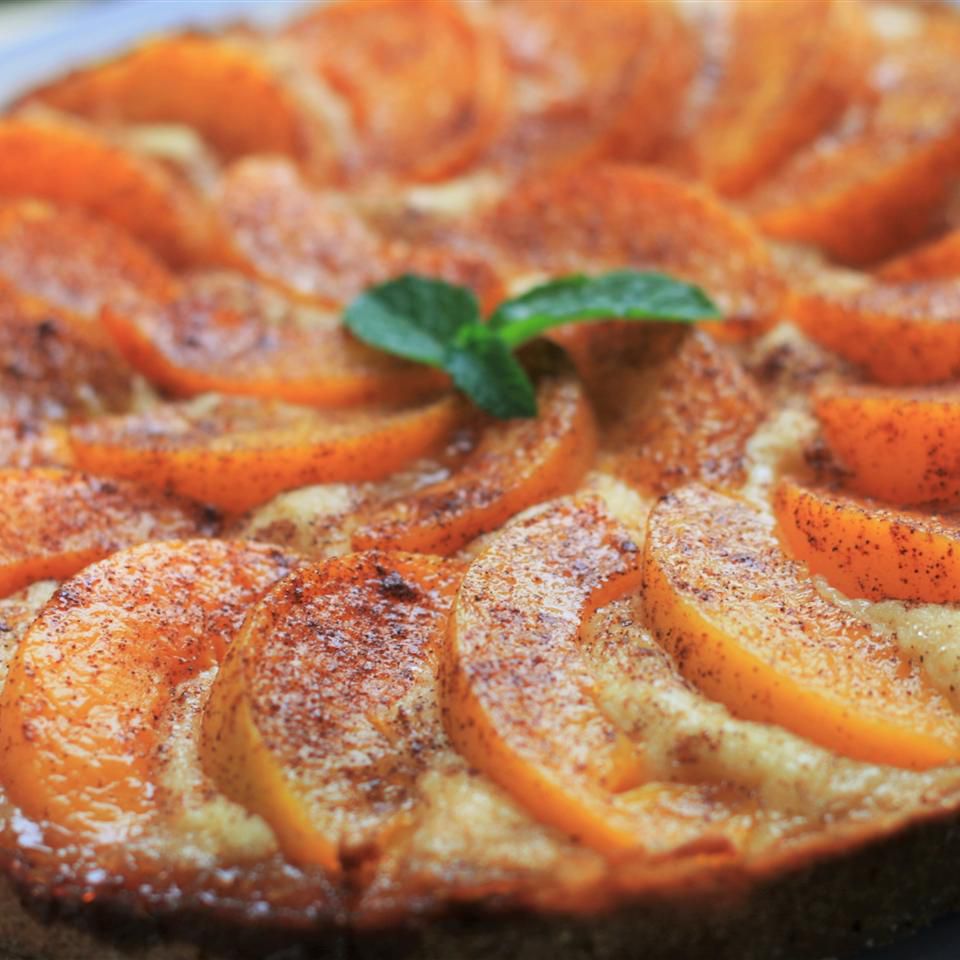 A closeup of a cake decorated with peach slices topped with cinnamon sugar