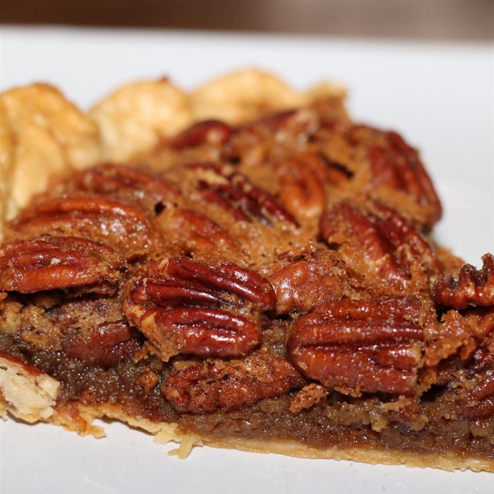 a closeup of a slice of pie decorated with pecan halves