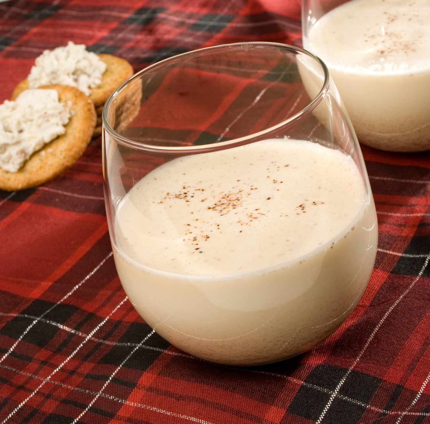 a glass of eggnog on a red plaid background