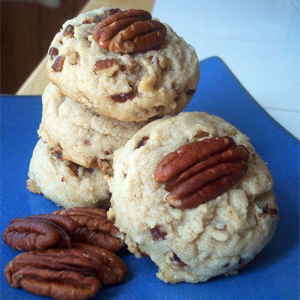 a stack of pecan cookies garnished with pecan halves on a blue background