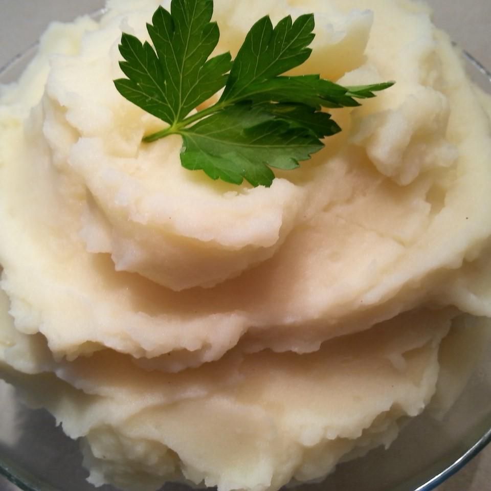 bowl of fluffy mashed potatoes topped with butter and parsley