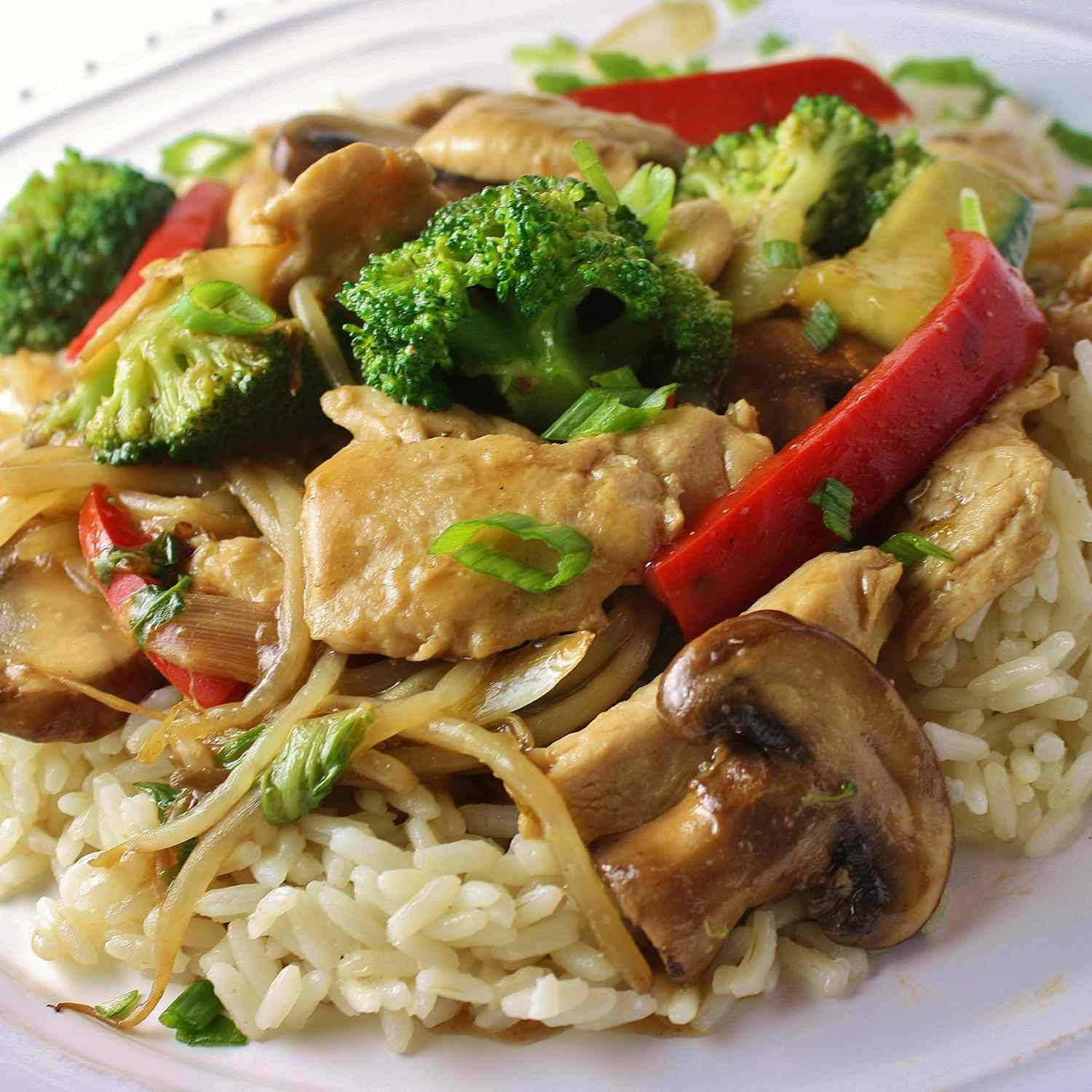 a colorful stir-fry of chicken breast strips, red bell pepper, broccoli florets, and sliced mushrooms on white rice