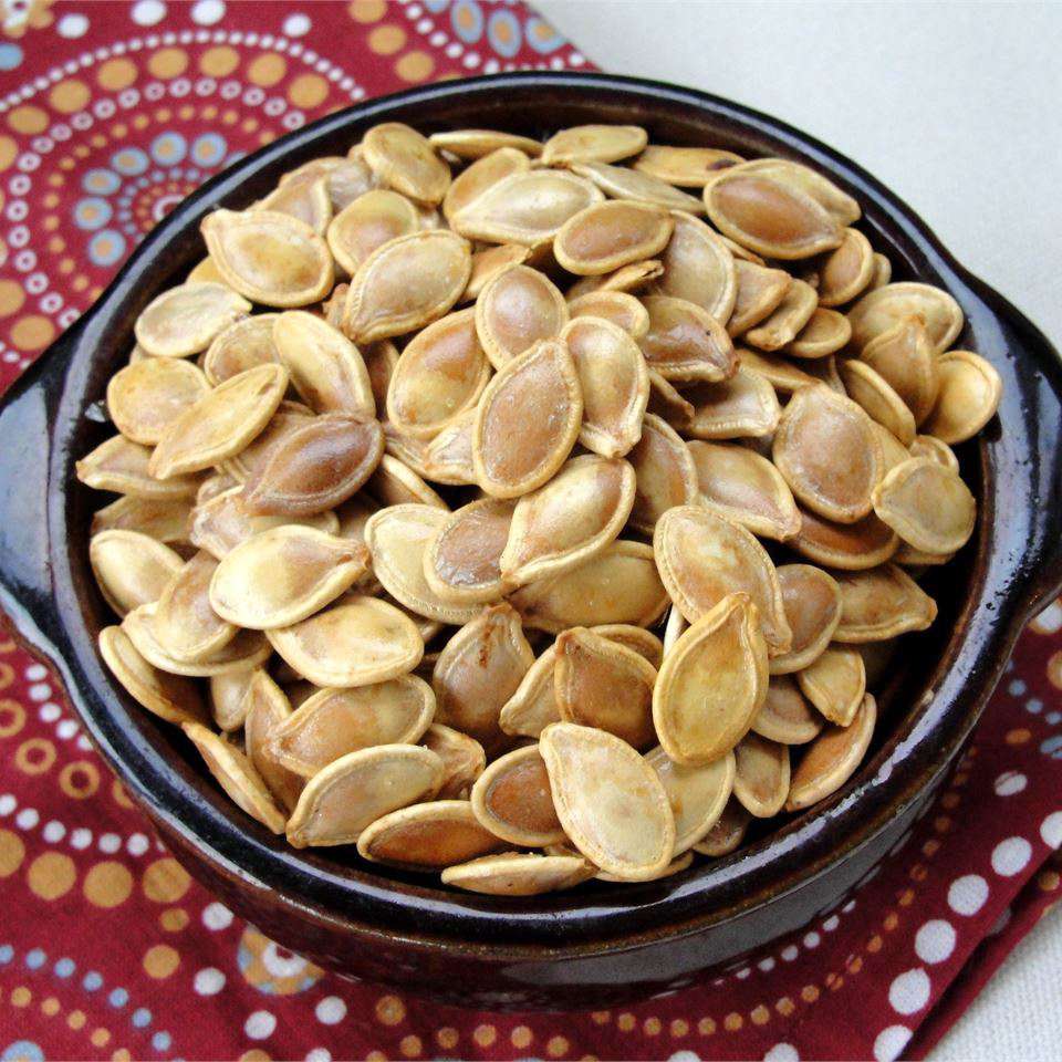 top-down view of pumpkin seeds in a black bowl