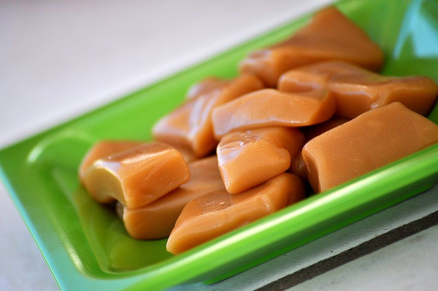 a square green plate holding fresh cut caramels
